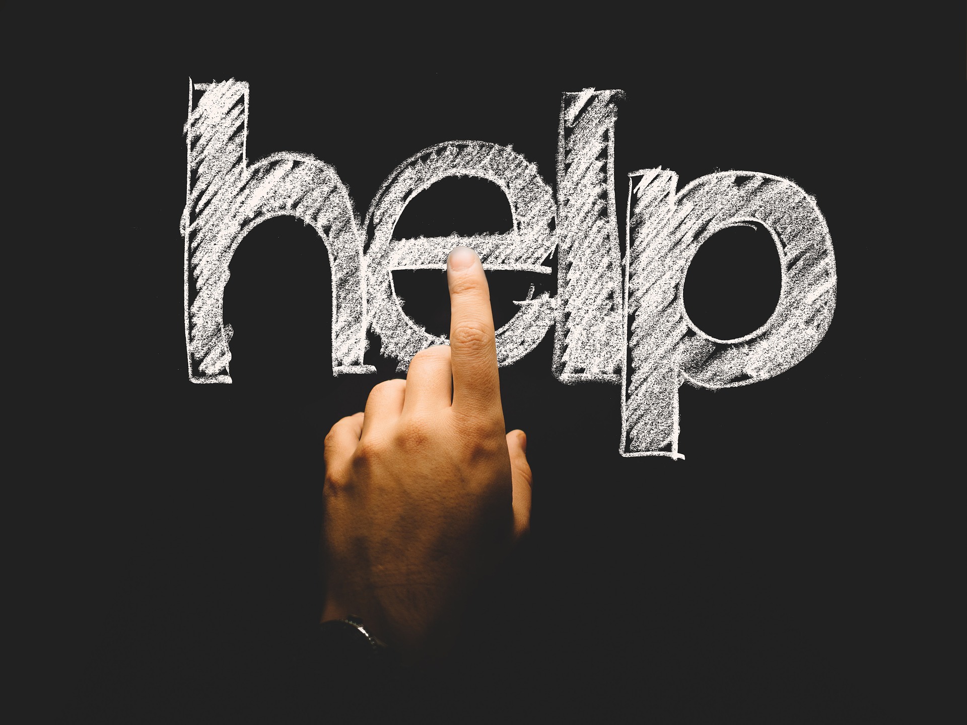 Hand pointing at chalkboard text "help"
